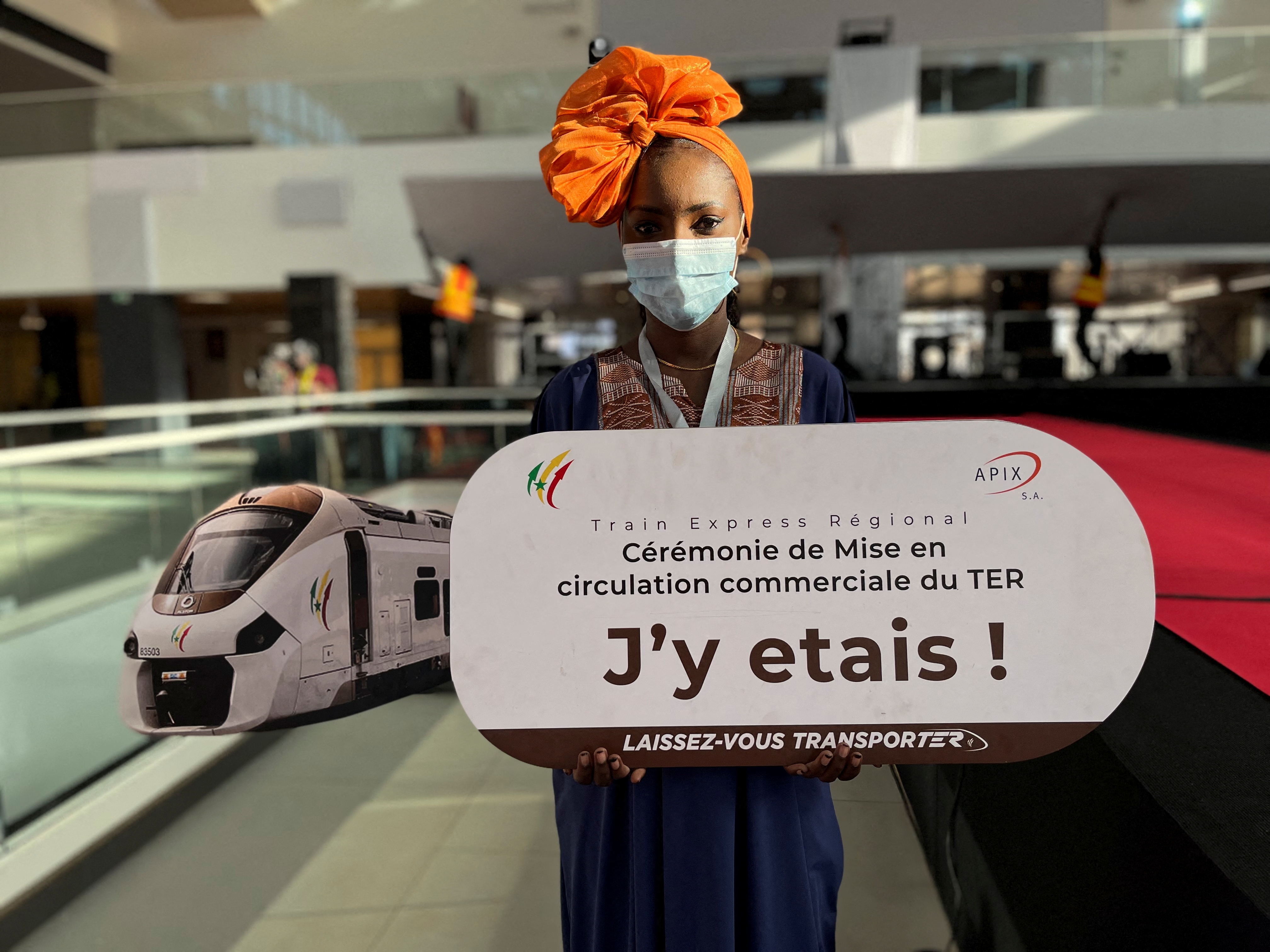 A hostess holds a sign at Senegal's new commuter train station during the launch ceremony of the Regional Express in Dakar, Senegal, December 27, 2021. The sign reads: TER commercial circulation launch ceremony. I was there! Let yourself be transported. REUTERS/Elodie Toto