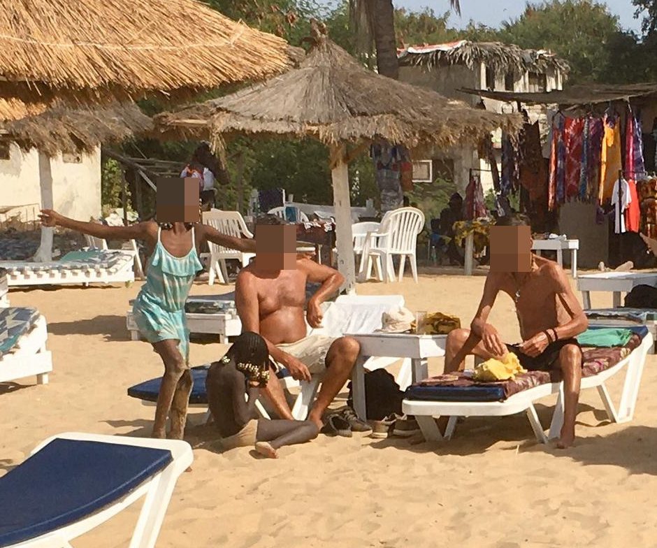  Two school-age girls play at the feet of two men, their mums nowhere in sight