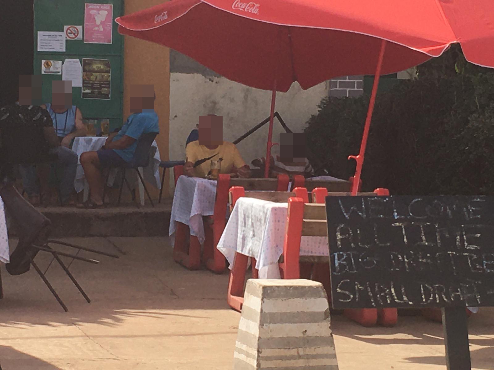  A tourist, in the yellow top, sits beside a young black boy at a café