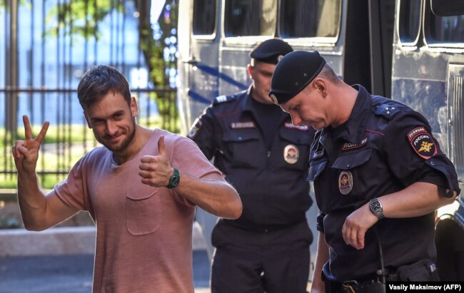 Pyotr Verzilov walks with police during a court hearing at a courthouse in Moscow on July 31, 2018.