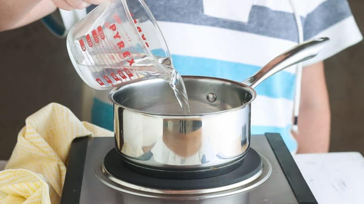 Pouring water into a pot to make simple syrup.